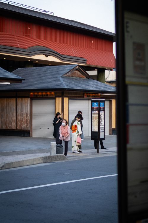 Free Street view of individuals waiting at a bus stop in Kyoto, Japan, during the day. Stock Photo