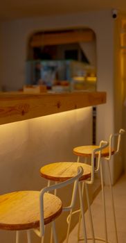 Warm and inviting cafe interior with modern wooden stools and soft lighting.