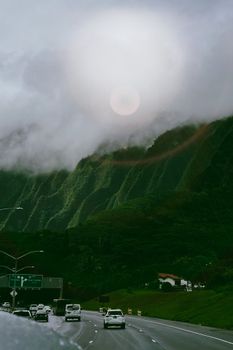 Highway drive with lush mountains and misty clouds creates a serene landscape.