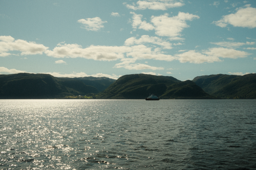 Free Tranquil lake scene with a boat and mountains under a sunny sky. Stock Photo