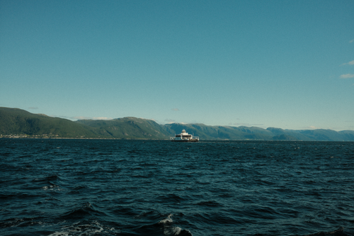 Free A beautiful ocean view with mountains and a ferry under a clear blue sky. Stock Photo