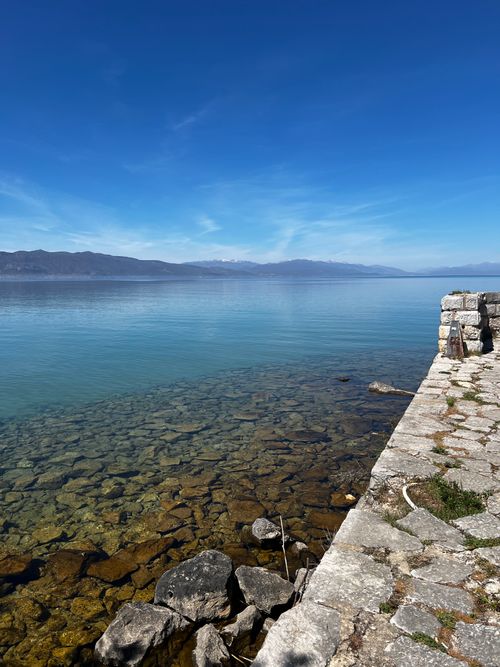 Free Beautiful view of Lake Ohrid with crystal clear waters and rocky shoreline under a vivid blue sky. Stock Photo