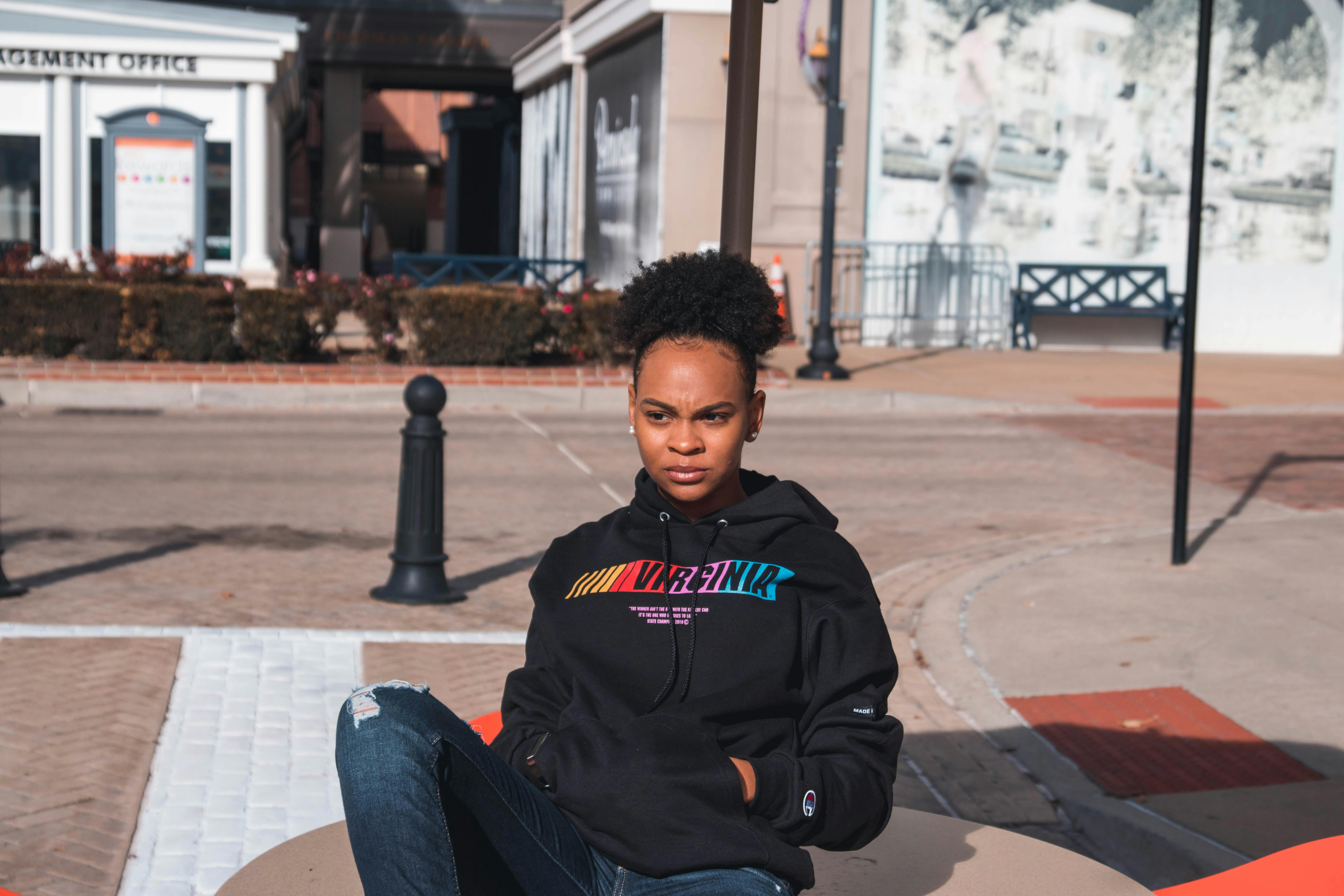 Person Wearing Black Hoodie and Blue Denim Jeans Sitting on Car