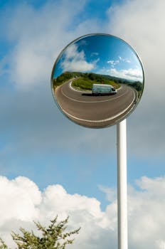 在凸面镜中，晴天反射的车辆捕捉到高速公路的弯曲和蓝天