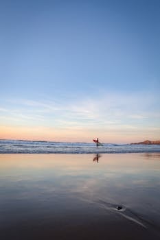 在日落时分，一名冲浪者在宁静的巴斯克乡村海滩上捕捉海浪