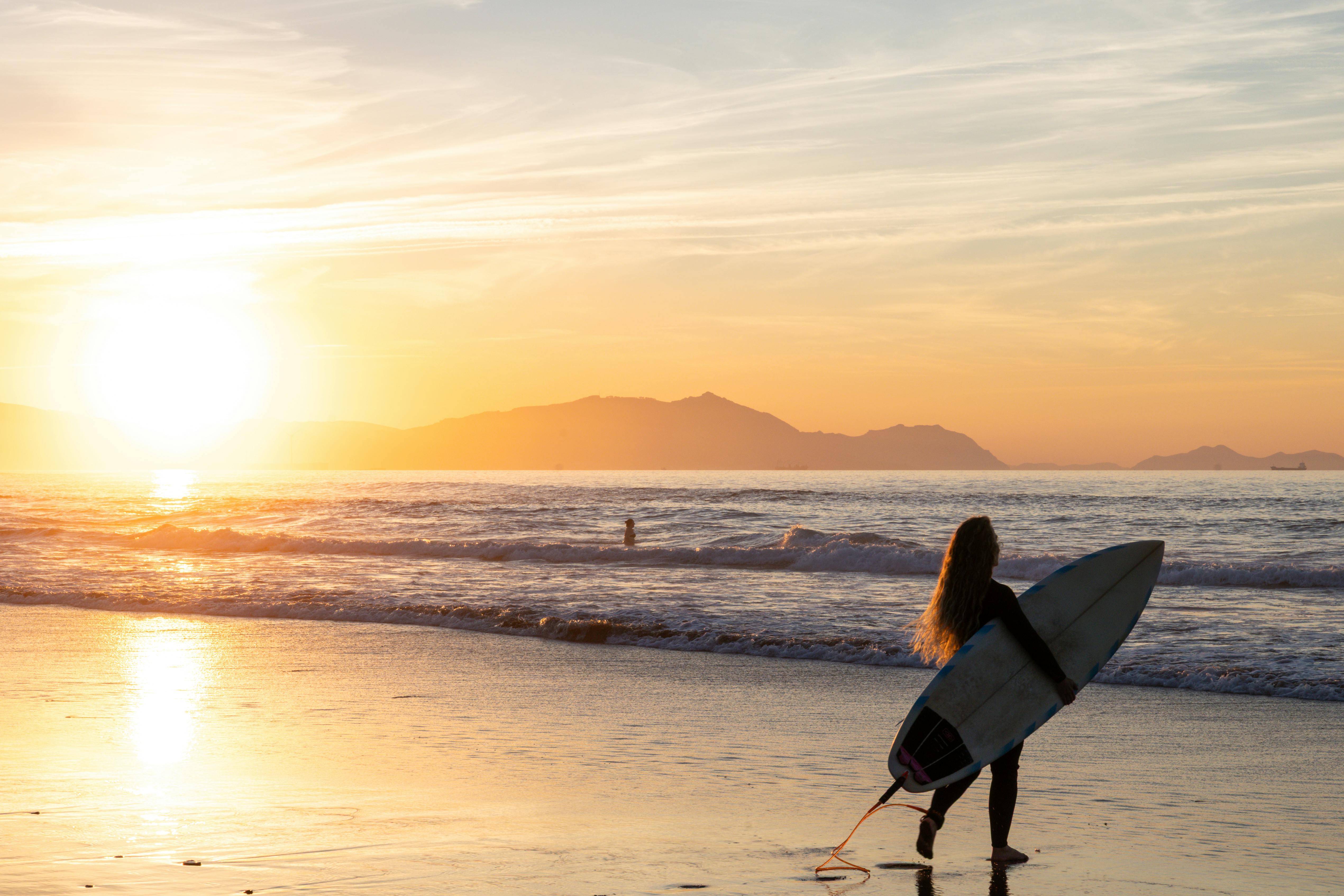 冲浪者凝视着令人惊叹的帕斯·瓦斯科日落，手持冲浪板