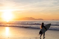 冲浪者凝视着令人惊叹的帕斯·瓦斯科日落，手持冲浪板