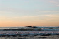 日落时分，巴斯克海岸，冲浪者在宁静的海洋中冲浪