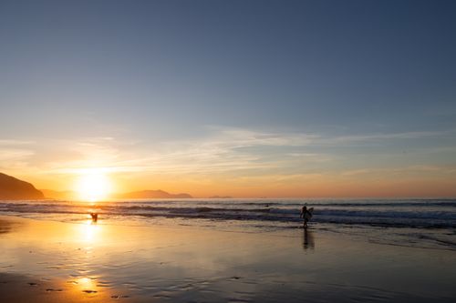 Free Surfer enjoying a vibrant sunset at País Vasco, Spain's stunning coastline. Stock Photo