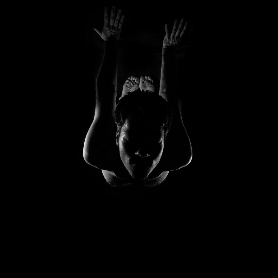 Low-key silhouette of a person folding forward in darkness — Perry Sore on Pexels