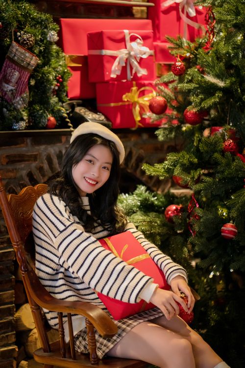 Free Smiling woman sitting by Christmas tree with gifts, creating a warm holiday ambiance. Stock Photo