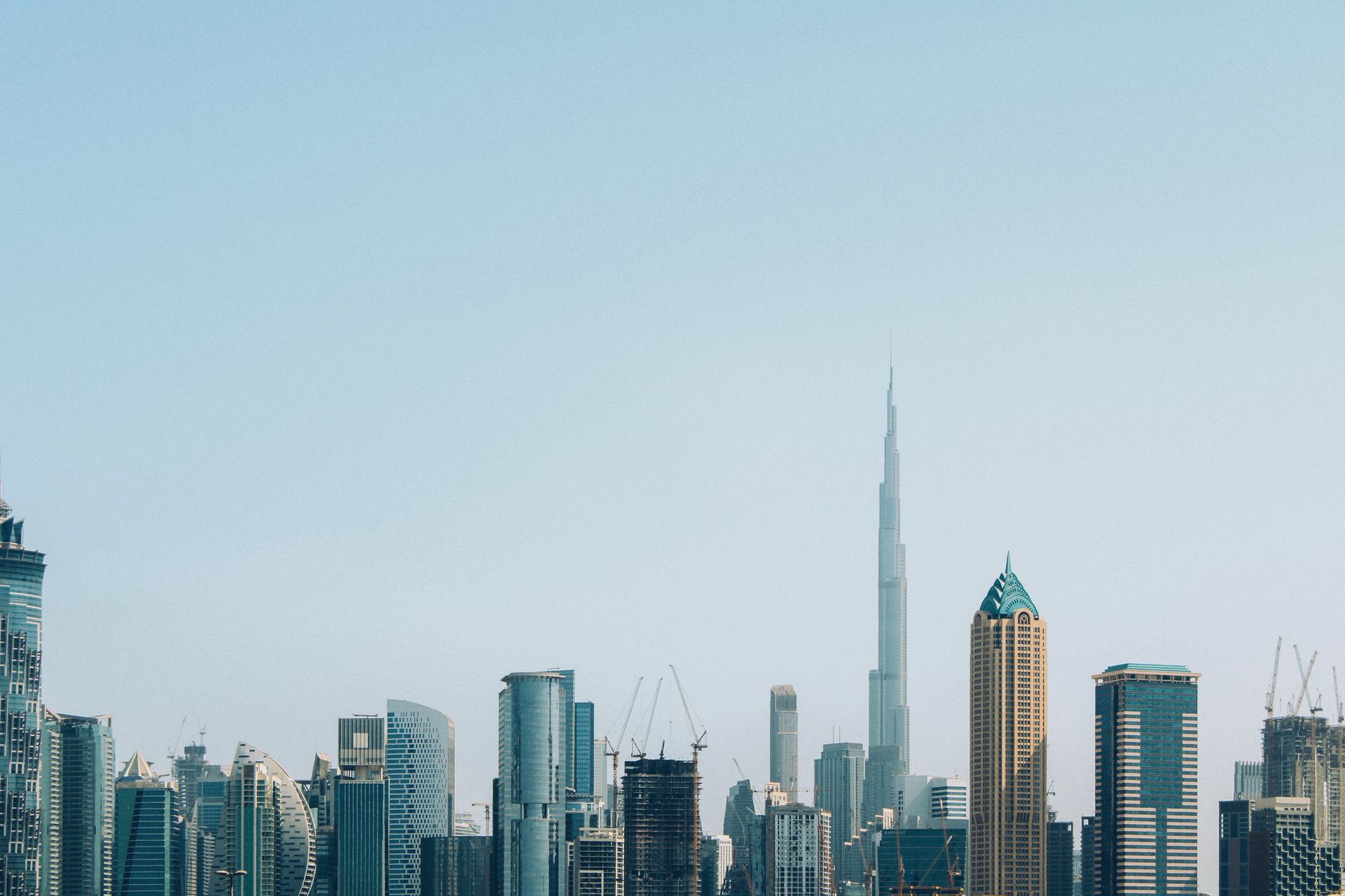 A stunning daytime view of Dubai city showcasing its modern skyline, iconic skyscrapers, and urban architecture under a bright blue sky