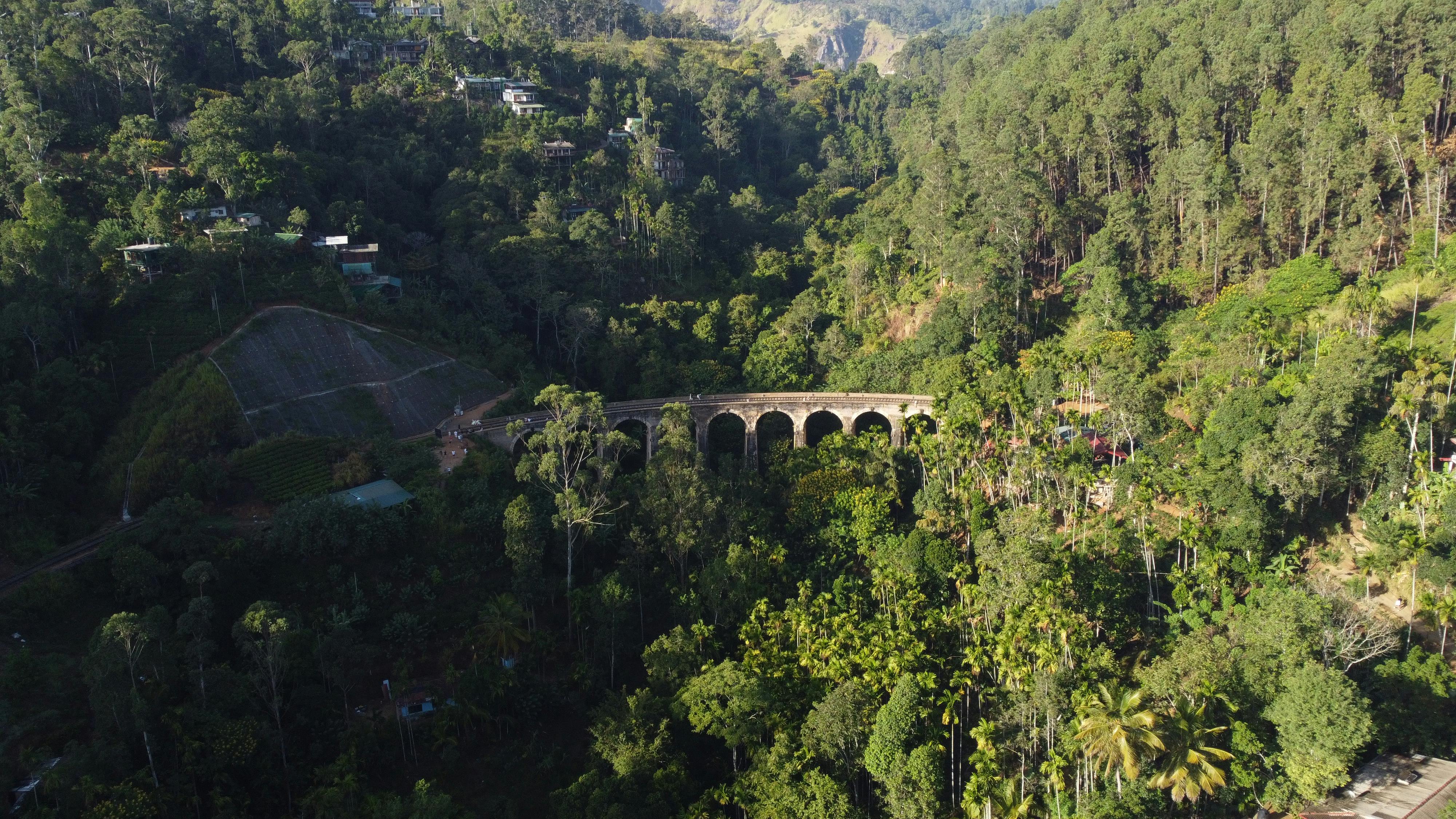 Drone shot of the iconic Nine Arches Bridge amidst lush green forests in Ella, Sri Lanka.