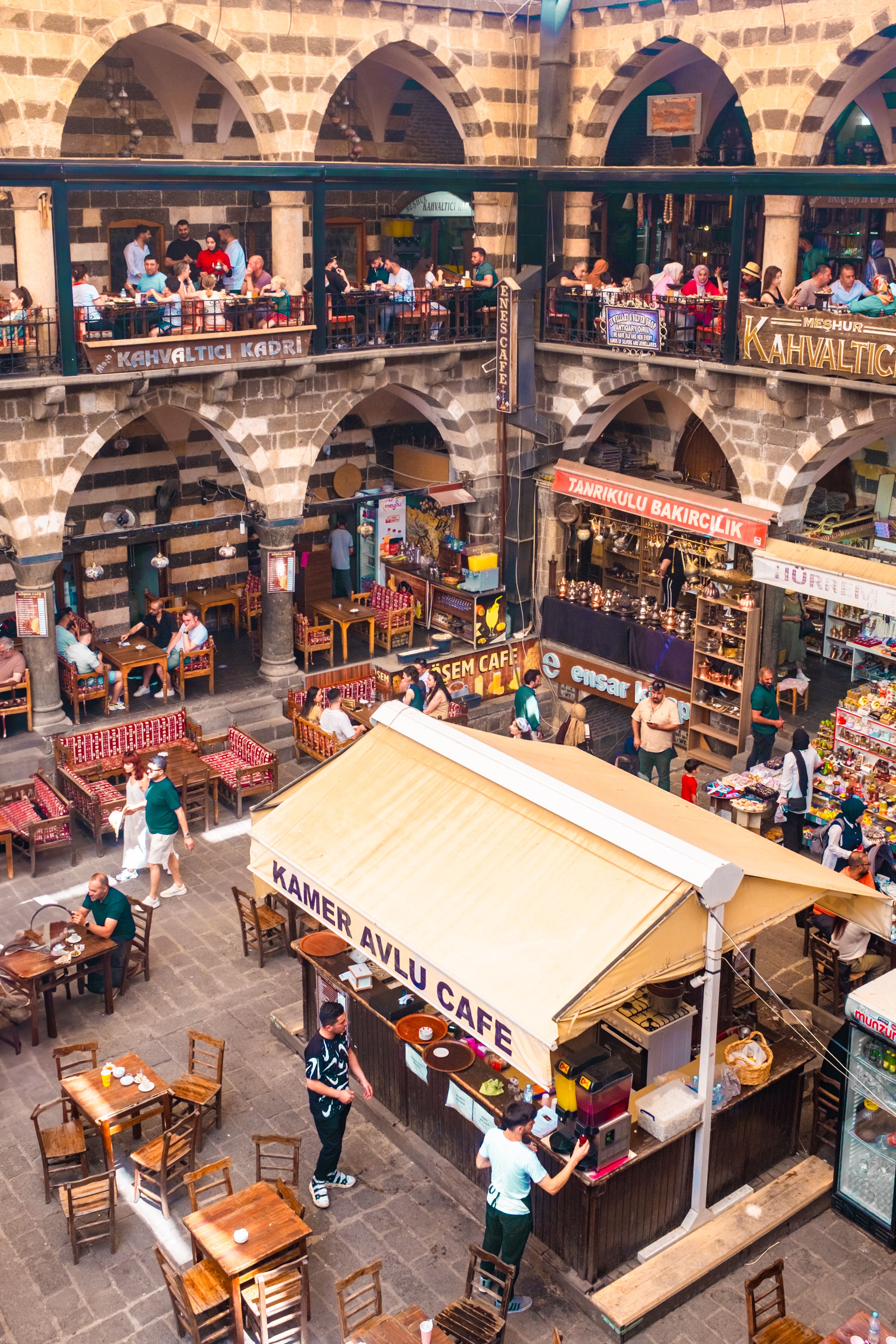 Vibrant scene at Diyarbakır's historic caravanserai with cafes and bustling visitors.