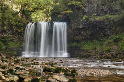 A serene waterfall surrounded by lush greenery in Brecon Beacons National Park, Wales.