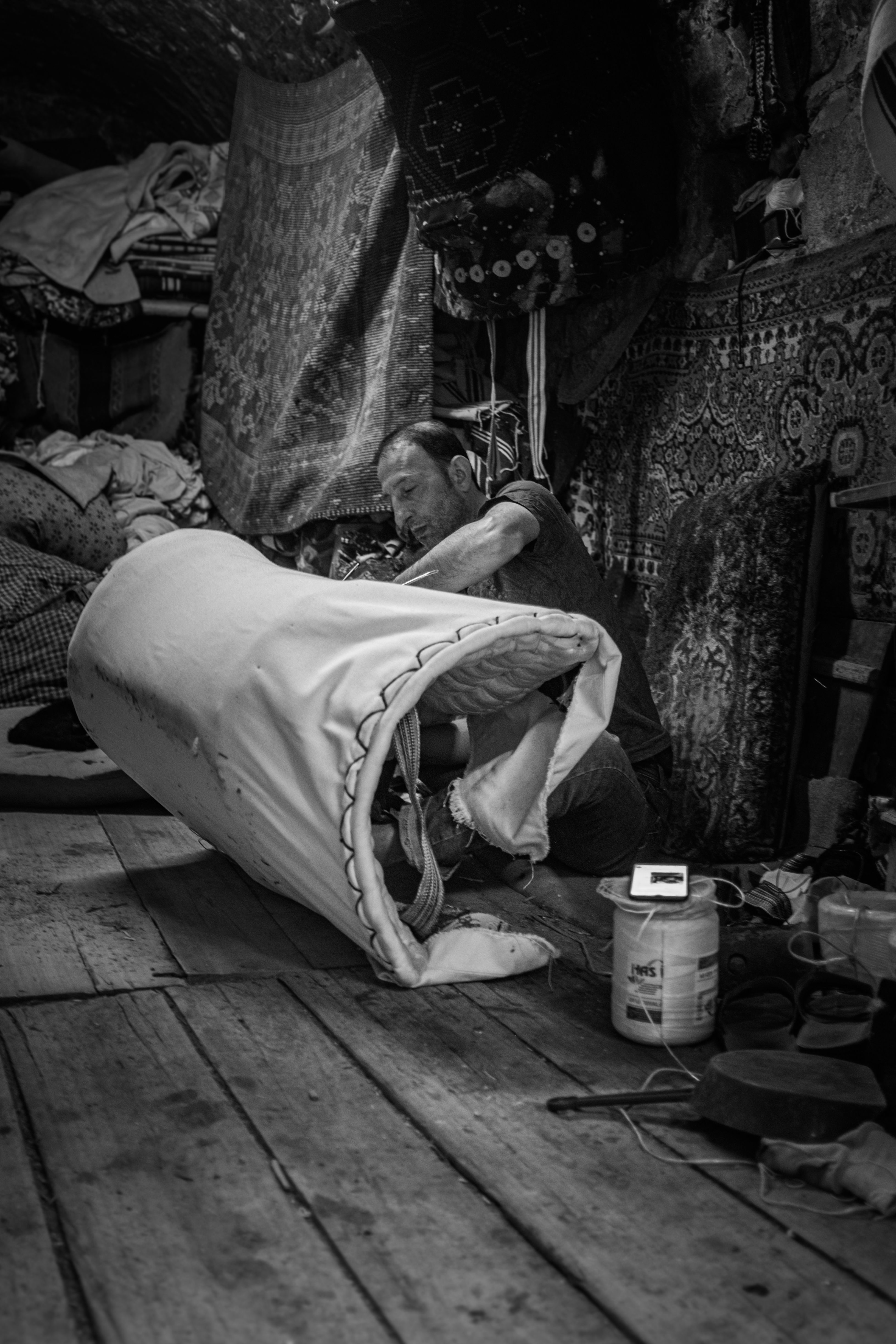 A skilled artisan working on traditional rug-making in a rustic workshop. Black and white photo.