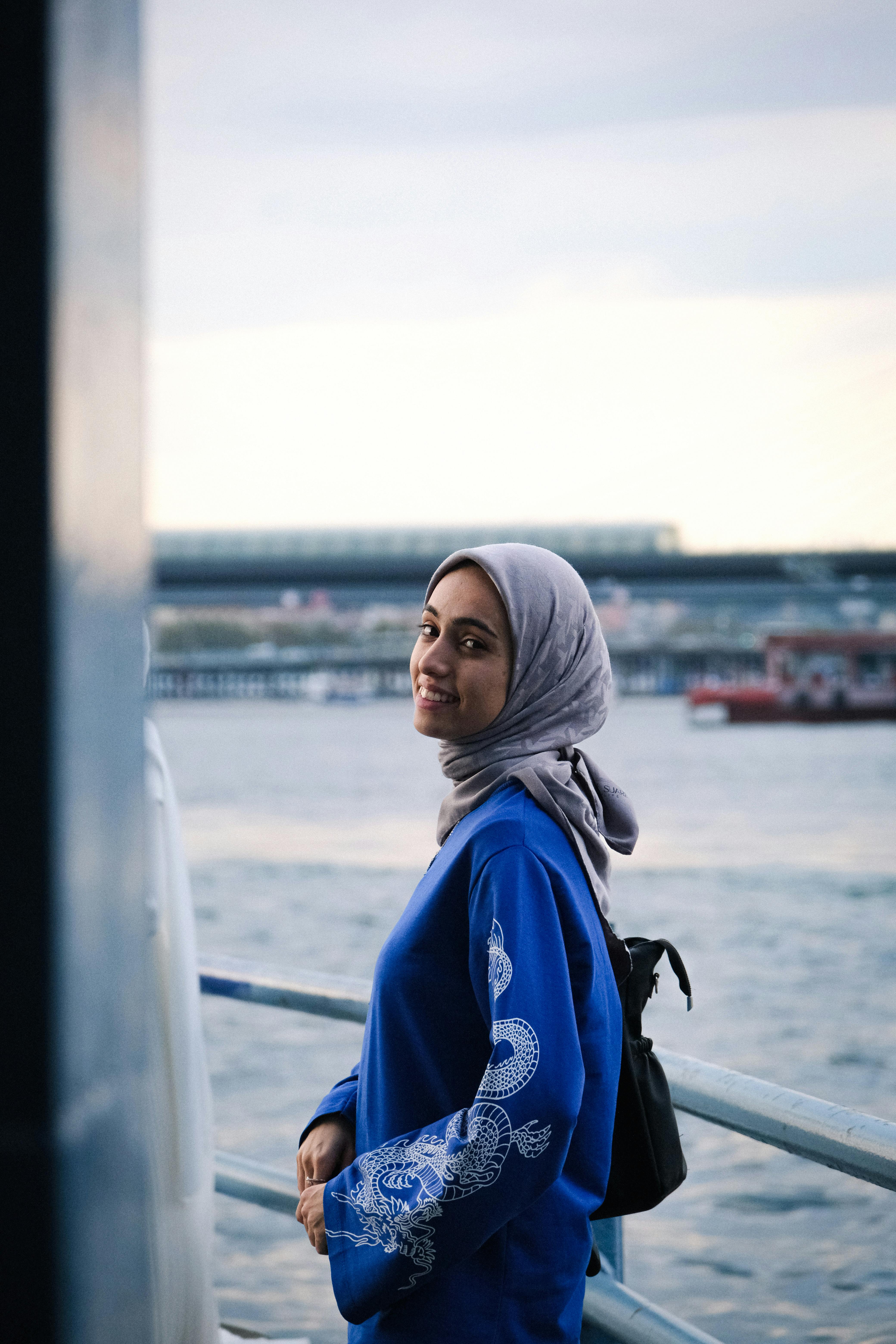 在城市的海滨，一位戴着蓝色头巾的微笑女子