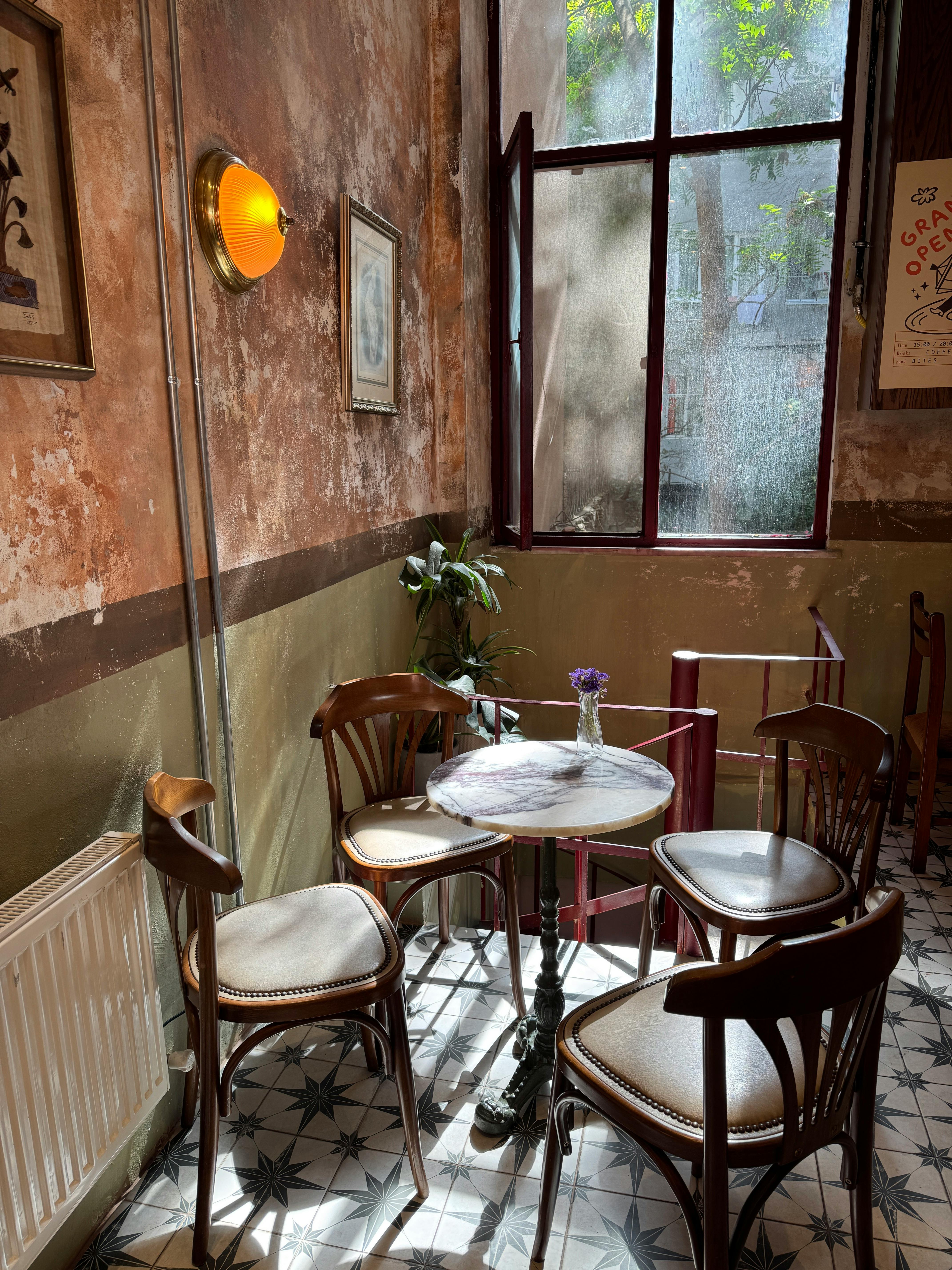 Gratuit Atmosferă fermecătoare de cafenea, cu decor vintage, interior luminos și scaune din lemn. Fotografie de stoc