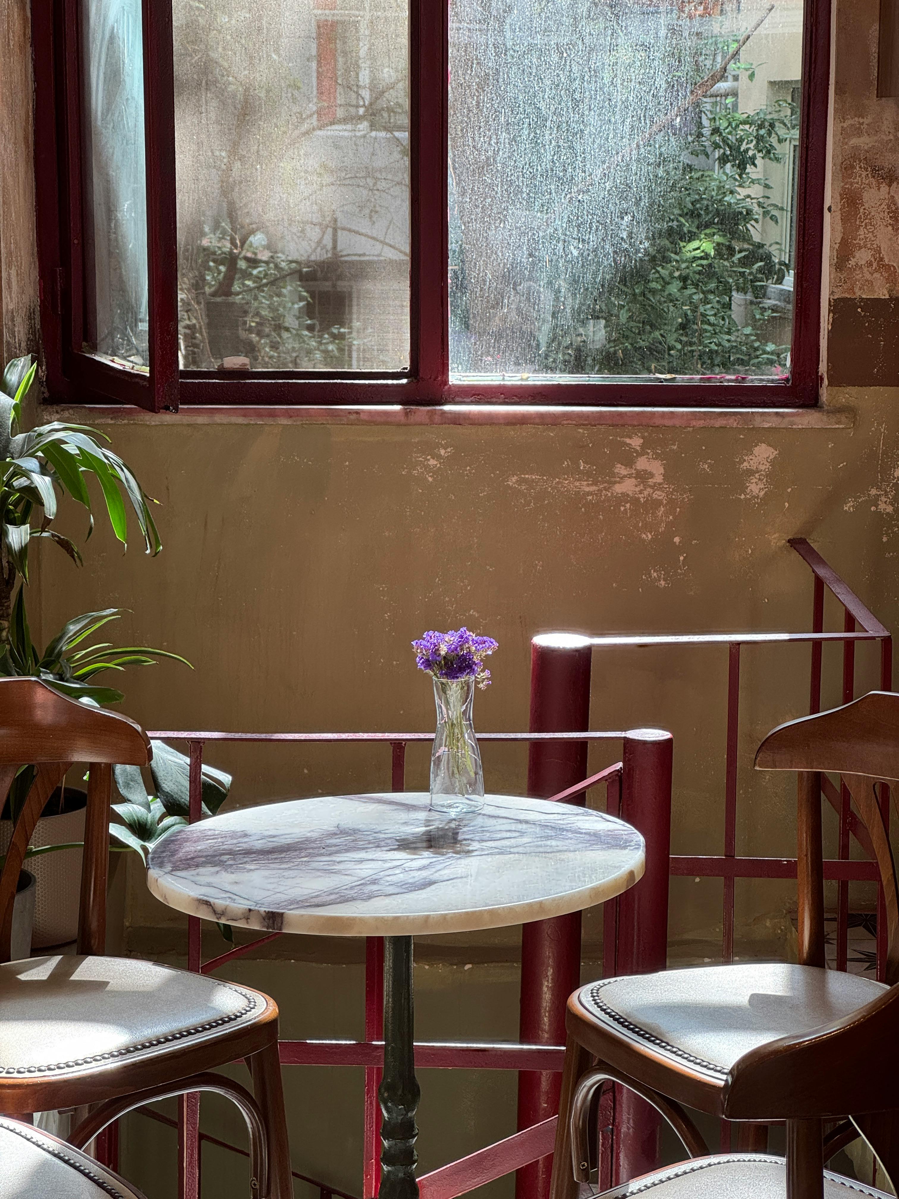 Gratuit O cafenea fermecătoare, cu o masă scăldată în soare și flori, creând o ambianță caldă. Fotografie de stoc