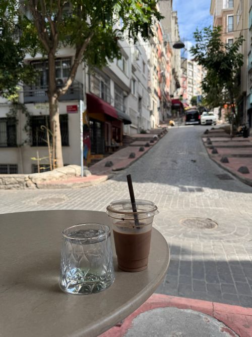 Free Enjoy an iced coffee at a quaint outdoor café overlooking a cobblestone street. Stock Photo