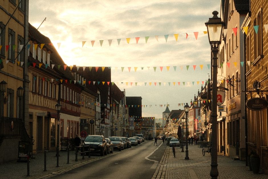 A picturesque street in Germany with colorful flags under a vibrant sunset sky.