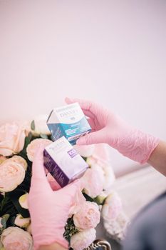 Pink gloved hands holding beauty products with roses in a spa setting.