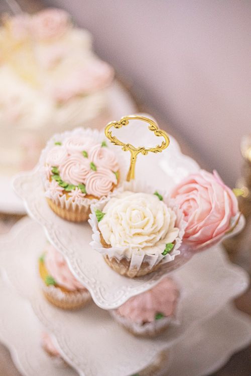 Free Delicate rose and floral cupcakes elegantly displayed on a tiered stand, perfect for a sophisticated event. Stock Photo