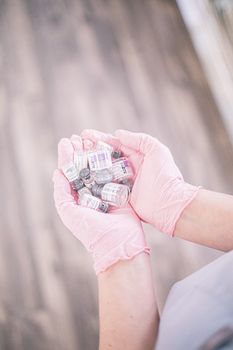 Aesthetic nurse wearing pink gloves holding vials of injectable treatments, symbolizing modern beauty care.