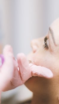 A professional performing a cosmetic injection on a woman's cheek in a clinic.