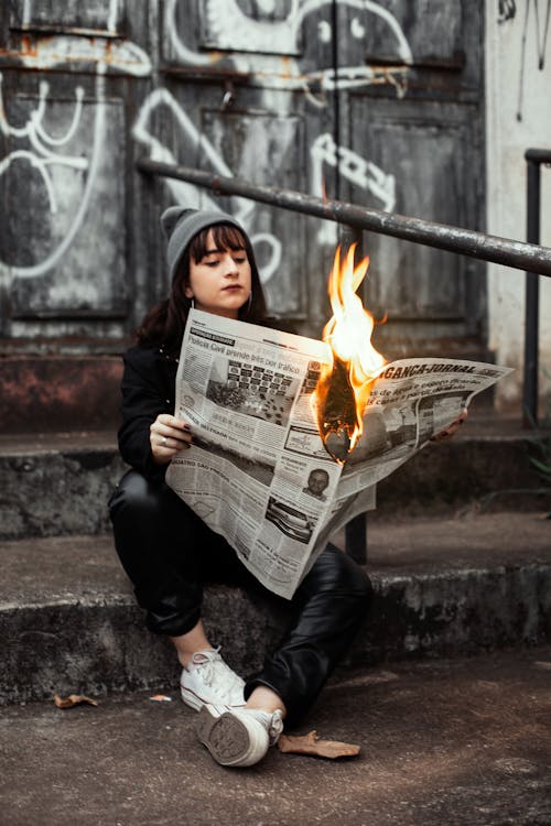 Женщина держит газету во время горения