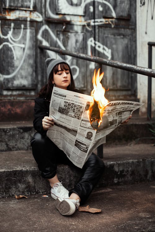 Woman Holding Newspaper While Burning