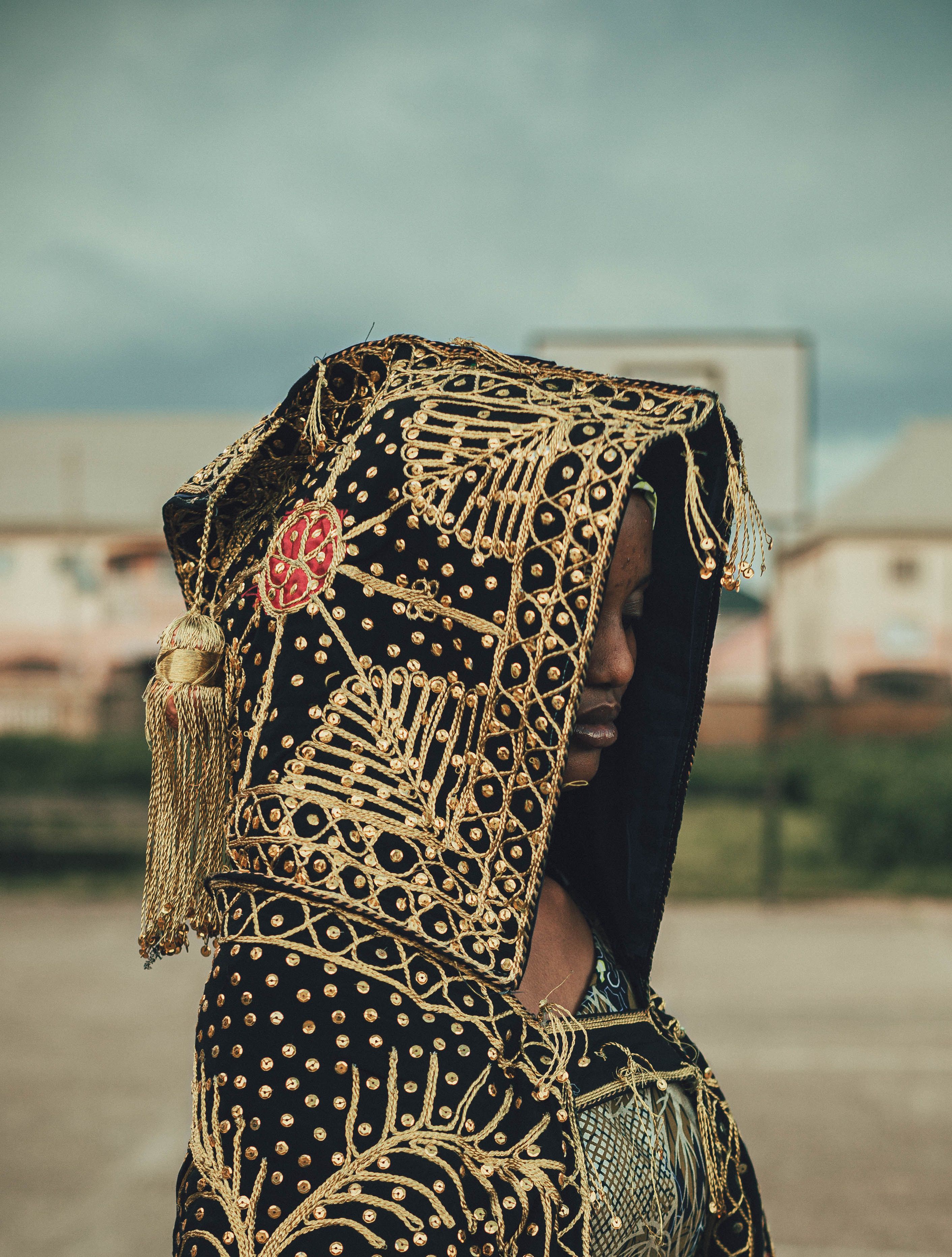 Profile of a person in ornate traditional African garment outdoors.