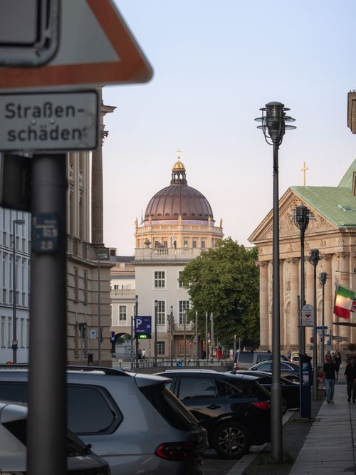 Free View of Berlin street featuring historic dome and architecture, with vehicles lining the urban scene. Stock Photo