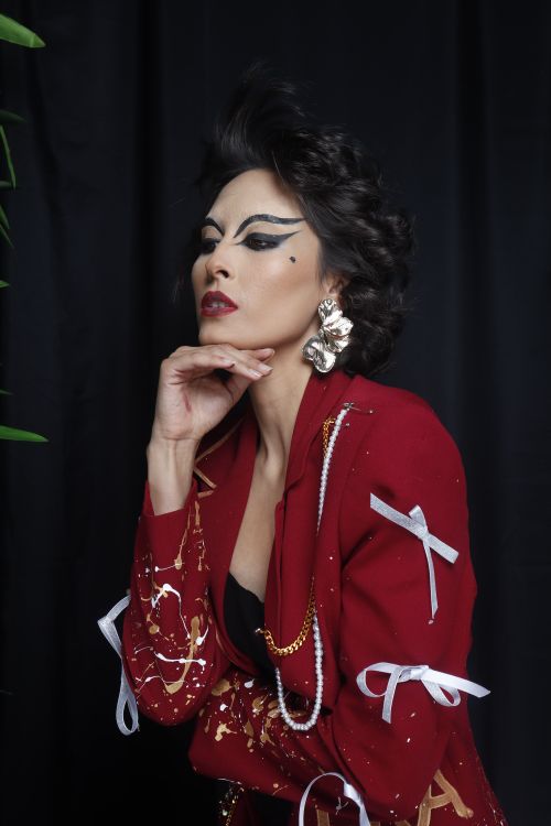Free Portrait of a stylish woman in a red jacket with striking eye makeup and large earrings Stock Photo