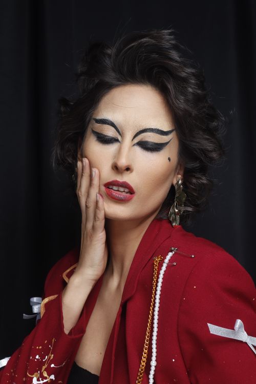 Free Portrait of a woman with striking makeup and stylish red attire, evoking dramatic fashion vibes. Stock Photo
