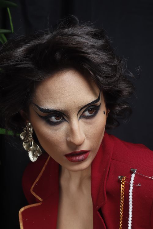 Free Striking portrait of a woman with bold makeup and statement earrings in a studio setting. Stock Photo
