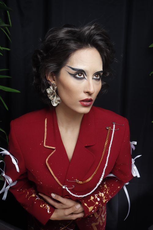 Free Striking portrait of a woman in red attire with bold makeup and earrings. Stock Photo