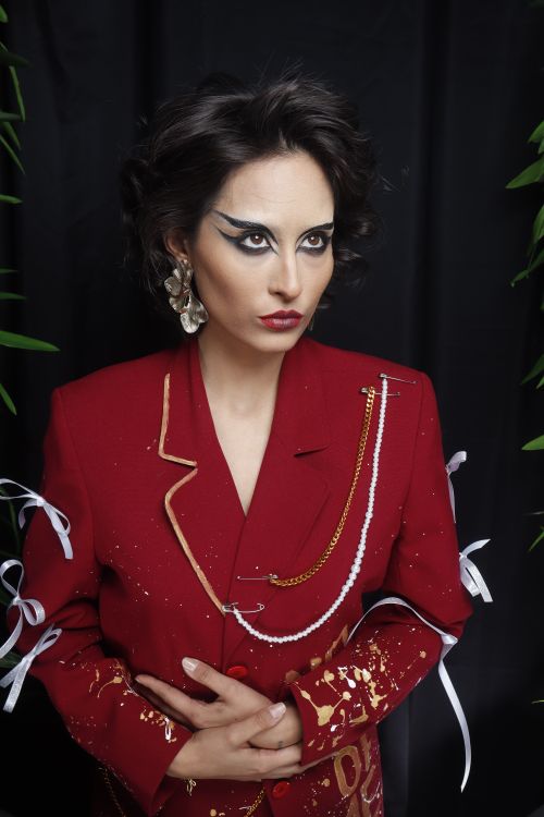 Free Portrait of a fashionable woman in a red jacket with bold eye makeup, embodying elegance and style. Stock Photo