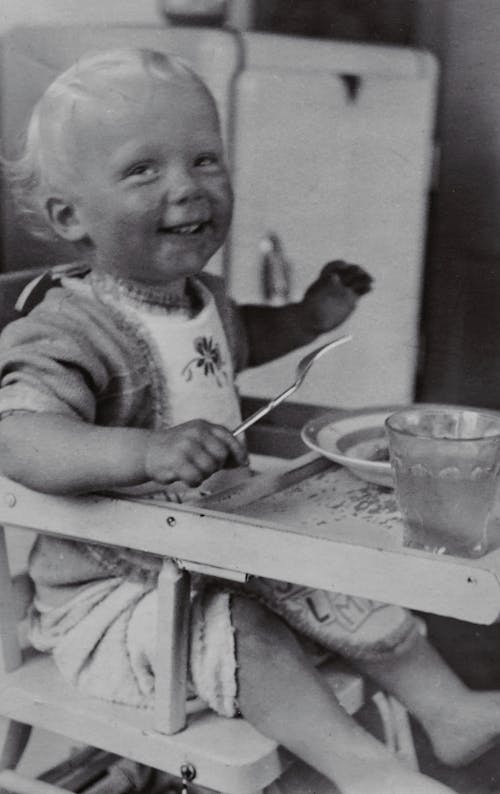 Free Photo of Happy Baby Sitting on High Chair Eating Stock Photo