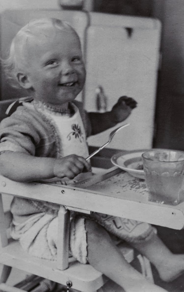 Photo Of Happy Baby Sitting On High Chair Eating