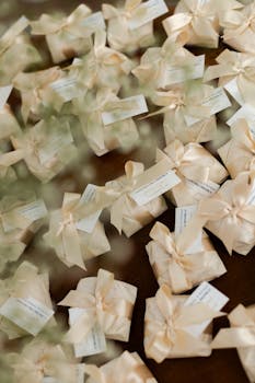 别致的婚礼礼物，装饰有奶油缎面蝴蝶结和标签，非常适合接待