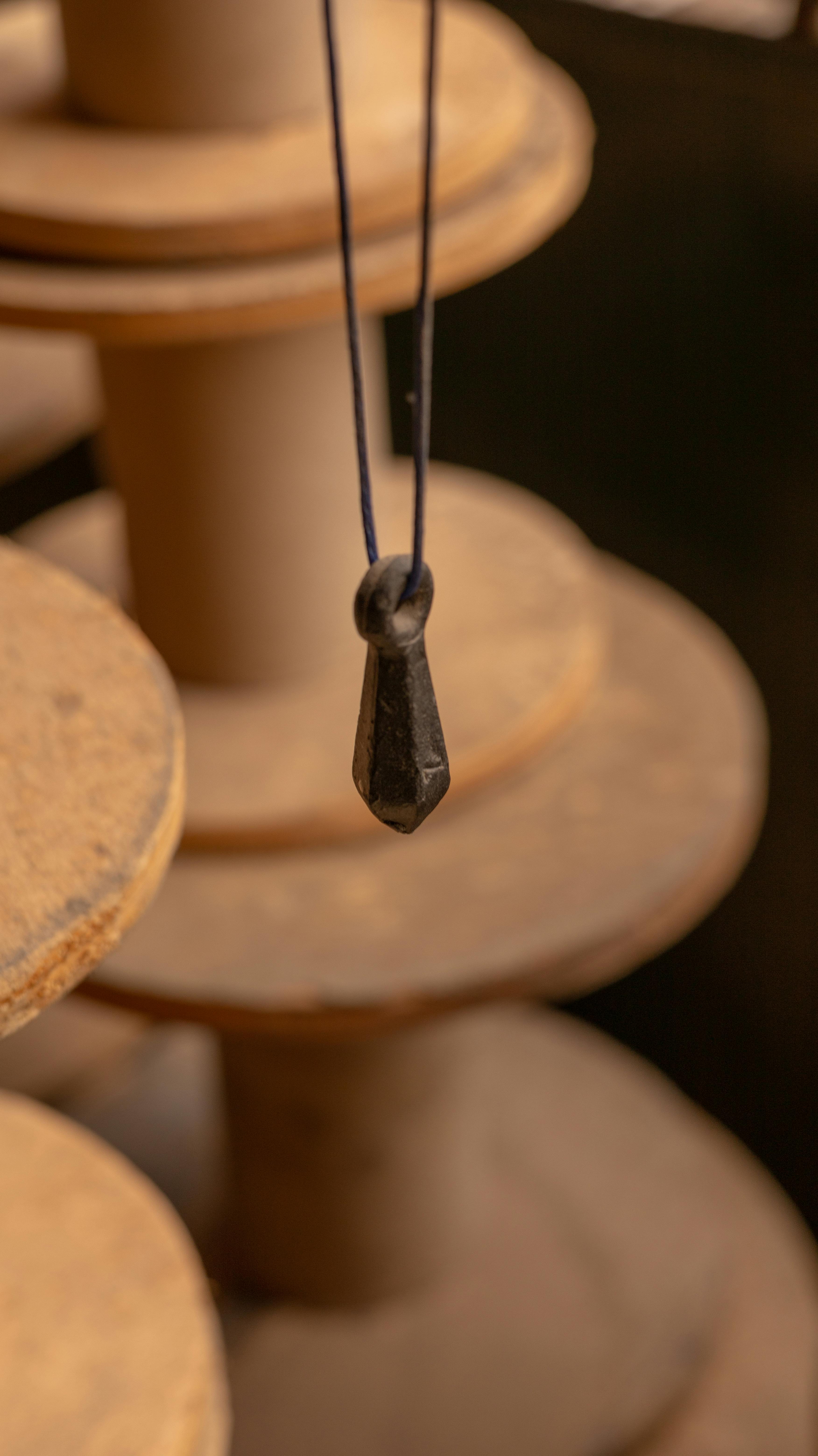 gratis Artistieke close-up van een metalen gewicht dat tussen houten spoelen hangt, wat textuur en vakmanschap laat zien. Stockfoto