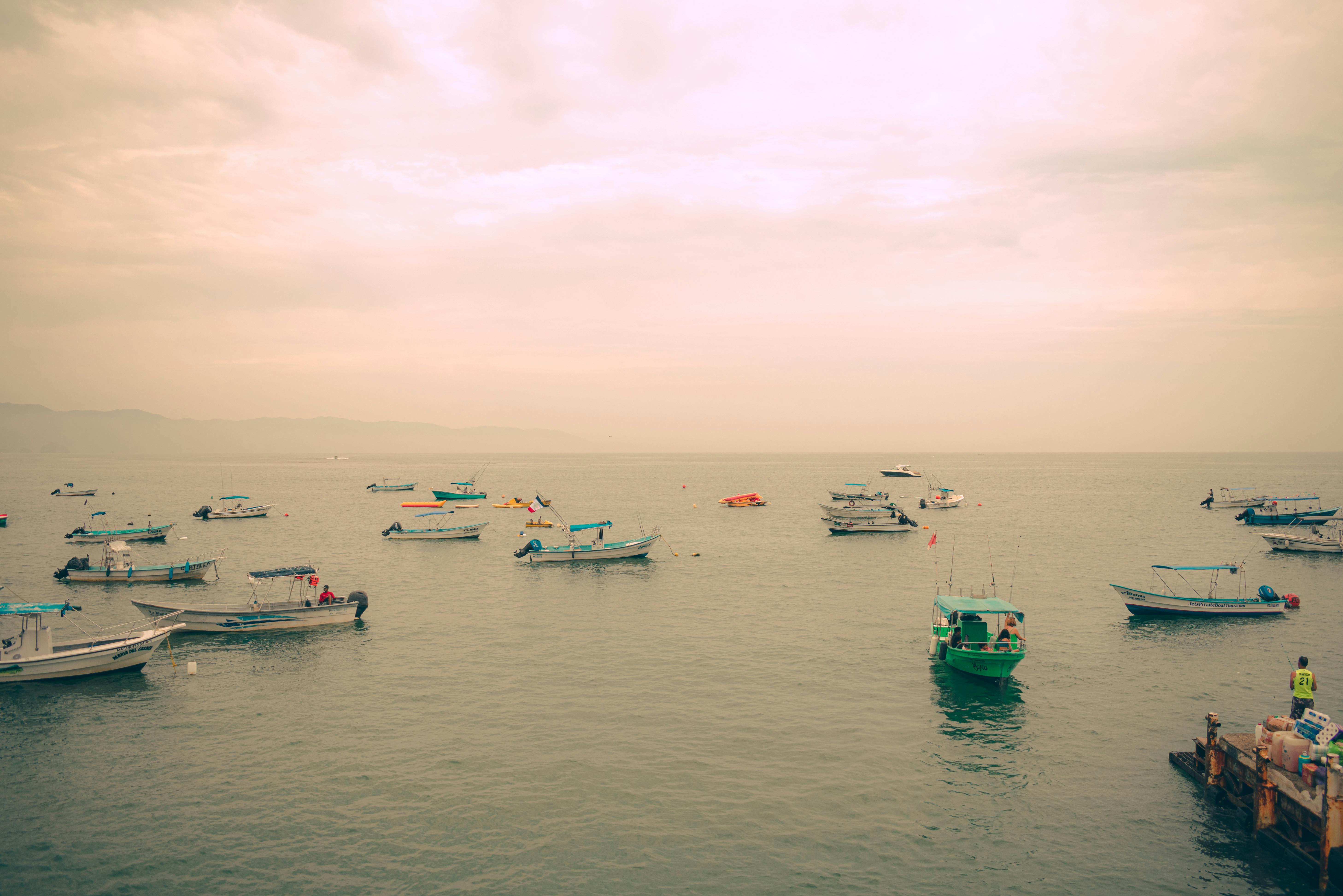 在宁静的日落天空下，平静的海面上漂浮着多艘船只，这些船只非常适合旅行和自然主题
