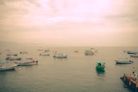 在宁静的日落天空下，平静的海面上漂浮着多艘船只，这些船只非常适合旅行和自然主题