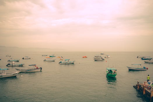 在宁静的日落天空下，平静的海面上漂浮着多艘船只，这些船只非常适合旅行和自然主题