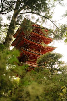 A traditional Japanese pagoda peeks through lush greenery, capturing the harmony of architecture and nature.