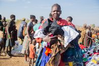 A community event where people receive donated clothing. A woman holds a bundle of clothes.