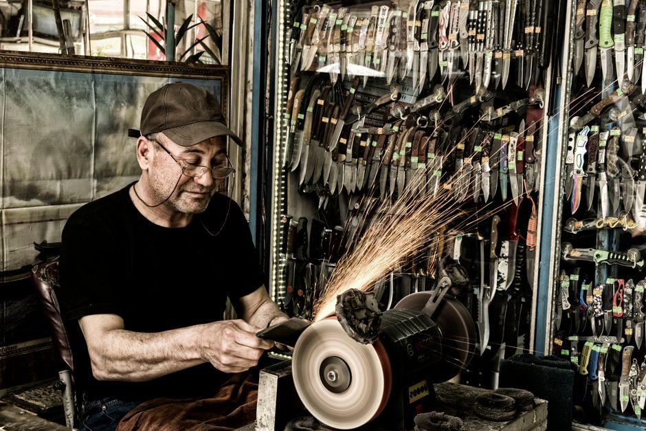 Experienced craftsman sharpening blades in a workshop — step-by-step technique for how to sharpen pruning shears in Surrey BC