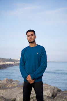 在岩石海边自信地站立的年轻人的肖像