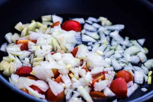 Free Close-up of chopped onions and cherry tomatoes in a pan, perfect for culinary themes. Stock Photo